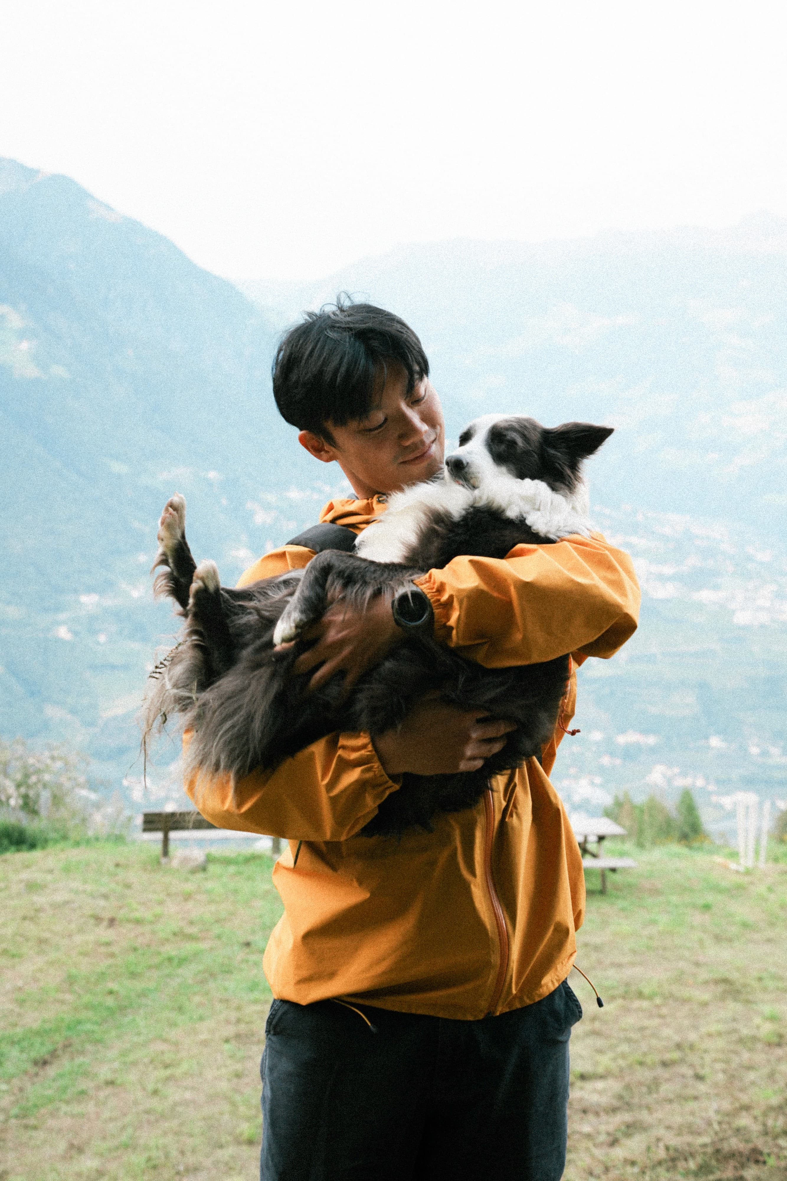 Bon holding a border collie in the mountains